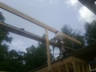 Carpenter setting a ridge beam over a new addition frame — Ice Dam Removal by Roofing Brothers in Canandaigua