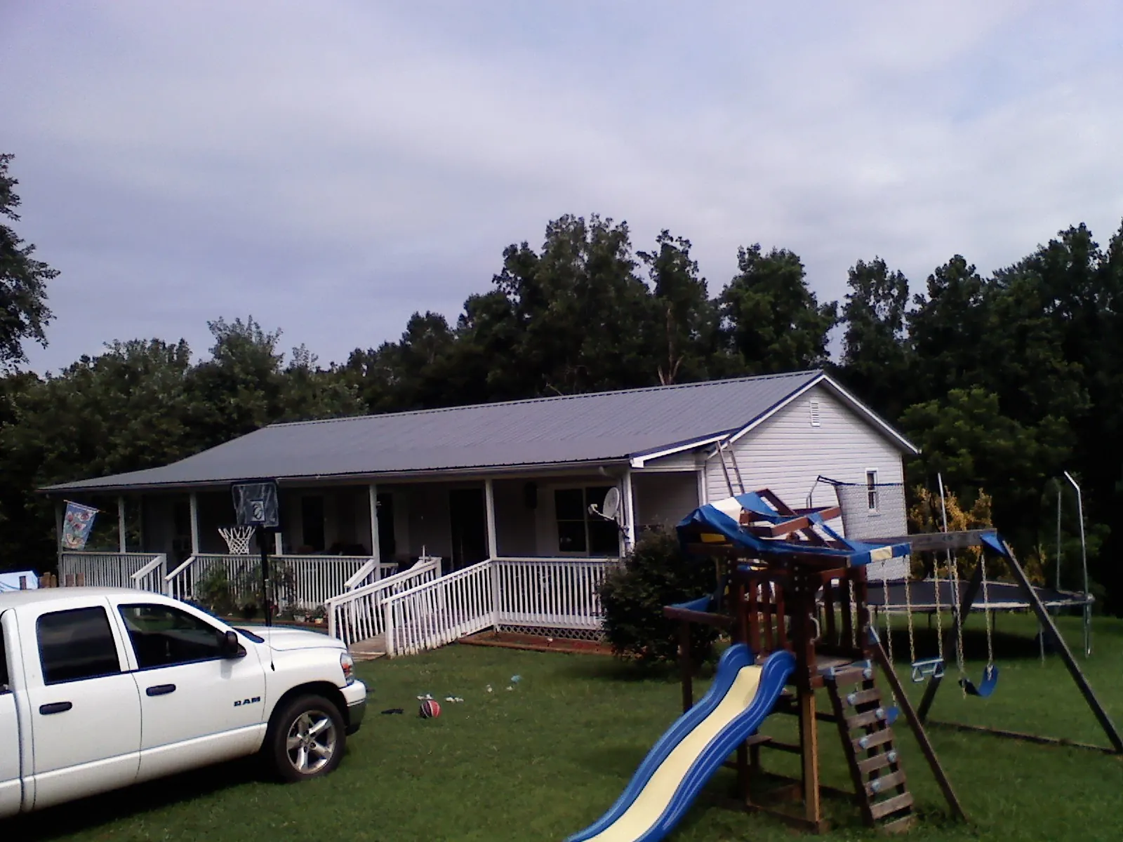 Dark metal roof on a country home with a full length front porch in Canandaigua