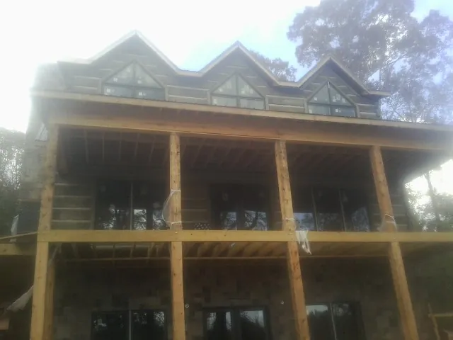 Dormers and porch framing on a large log home under construction — Roof Coating work by our crew in Canandaigua