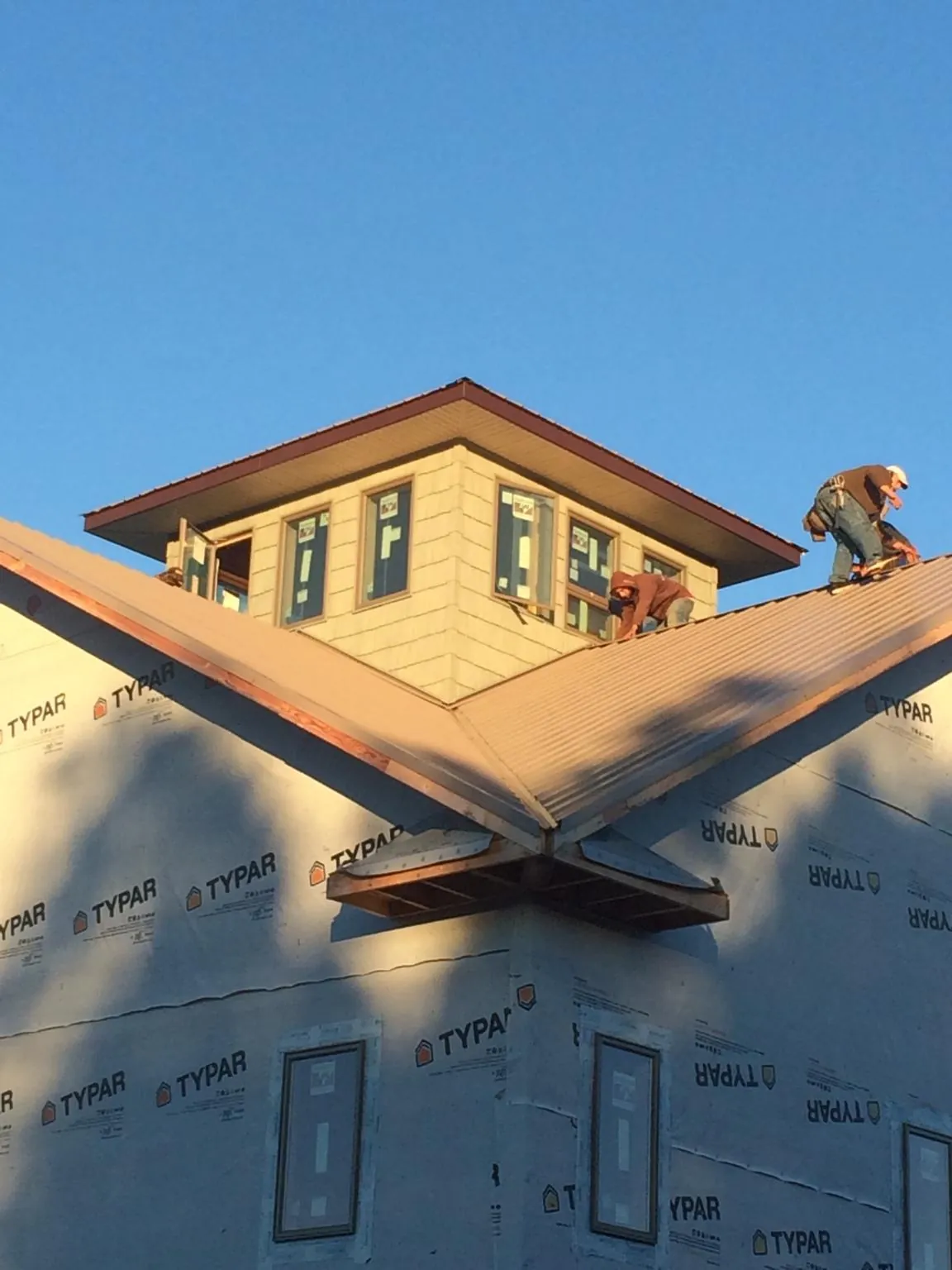 Roofers working around a rooftop cupola on a new metal roof at sunset — Roof Waterproofing in Canandaigua by Roofing Brothers
